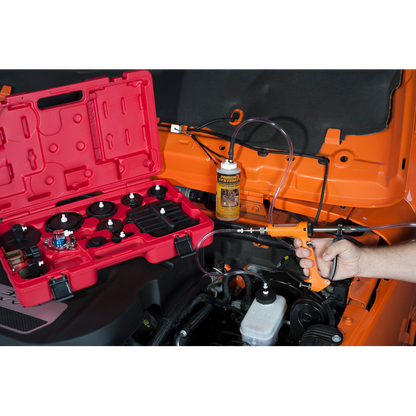 The image shows a person using a brake bleeding kit on a vehicle.  Brake bleeding involves forcing fresh brake fluid through the brake system to remove air bubbles, which can compromise the braking performance.  pen_spark