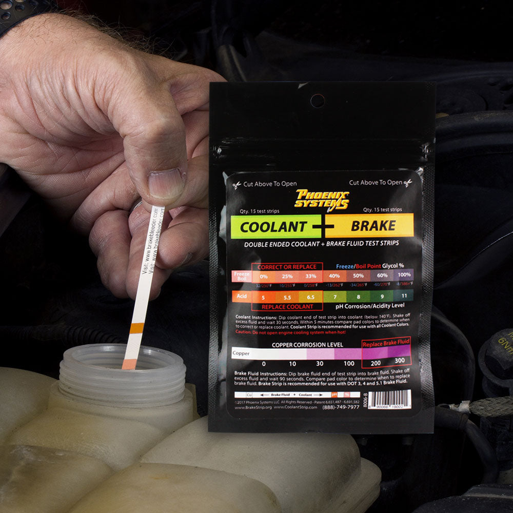 The image depicts a package of Coolant + Brake Fluid Test Strips by Phoenix Systems. It includes 15 strips with instructions for testing both coolant and brake fluid. To use, dip the designated end of the strip into the corresponding fluid, wait for the specified time, and compare the resulting pad color to a chart on the package to assess freeze/boil point, glycol content, corrosion levels, and the need for replacement.