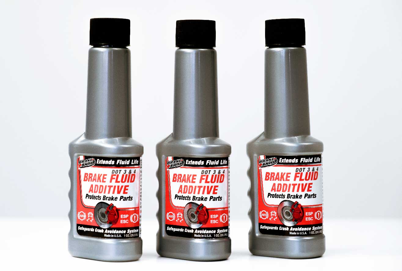 The image shows three identical bottles of ESPO brake fluid additive sitting on a table. The text on the label says that the additive is compatible with DOT 3 and DOT 4 brake fluid, and that it extends fluid life, protects brake parts, and safeguards crash avoidance systems. The text also says that the product is made in the USA.