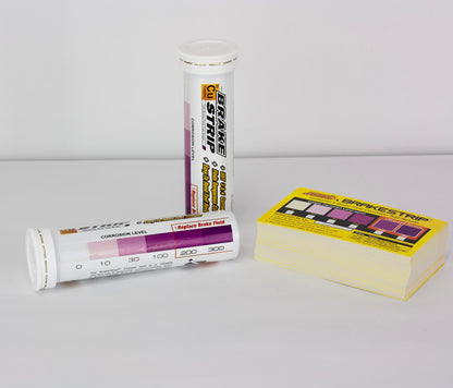 The image shows two containers of Phoenix Systems Brake Fluid Test Strips.  One container is a tube and the other is a box.  Text on the containers describes the product and its function. There is also a chart that appears to indicate a range of corrosion levels.