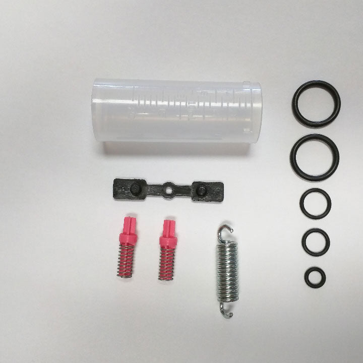 The image depicts a clear plastic container with a screw-on lid, likely for storing tools used in car maintenance. These tools, visible as hoses, adapters, and caps, are most likely used for a process called brake bleeding, which removes air bubbles to ensure the car's brakes function properly.